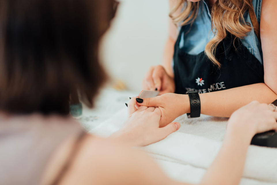 A person receiving a manicure from a nail technician, showcasing the practical skills taught in the course.